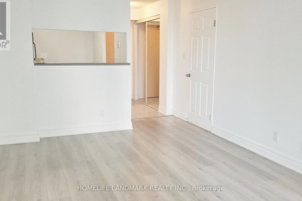 Living area with light grey laminate flooring, white walls, and pass-through. - 1410 - 24 Wellesley Street W, Toronto