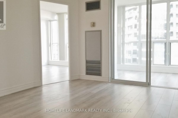 Empty room with light grey laminate flooring and large windows. - 1410 - 24 Wellesley Street W, Toronto