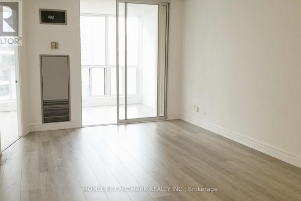 Room with light grey laminate flooring, white walls, and sliding glass doors. - 1410 - 24 Wellesley Street W, Toronto