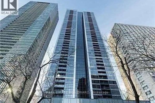 Low angle view of a tall glass condominium tower against a clear sky. - 1410 - 28 Ted Rogers Way, Toronto