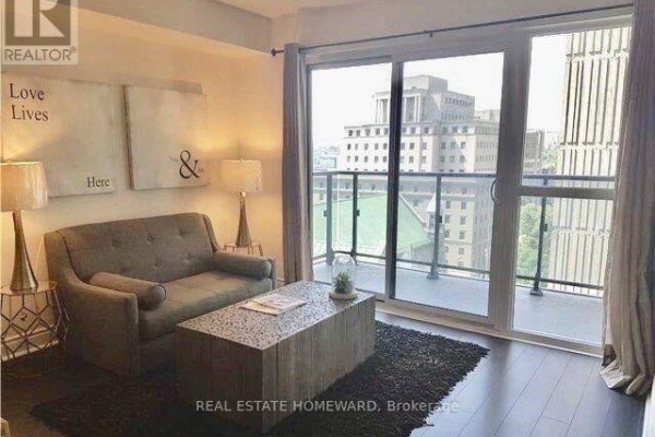 Living area with sofa, coffee table, and large balcony doors overlooking city buildings. - 1410 - 28 Ted Rogers Way, Toronto