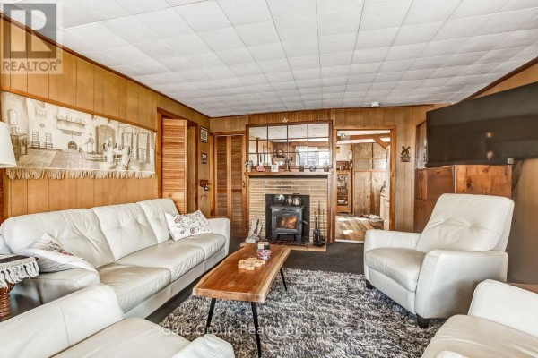 Dining area with a round wooden table, chairs, and a vintage wooden cabinet. - 1410 Dundas Street, Woodstock