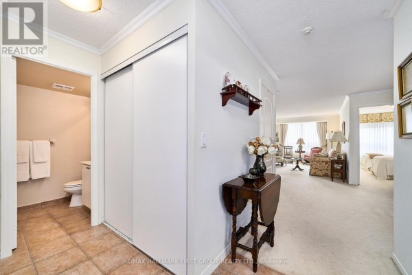 Hallway entrance with cream carpet, sliding closet doors, and view into living room. - 1411 - 1000 The Esplanade Road N, Pickering