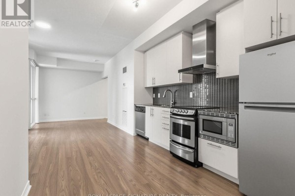 Open concept living area with a kitchen featuring white cabinets and stainless steel appliances. - 1411 - 352 Front Street, Toronto