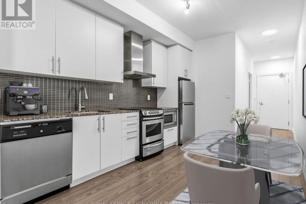 Modern kitchen with white cabinets, stainless steel appliances, and a glass dining table. - 1411 - 352 Front Street, Toronto
