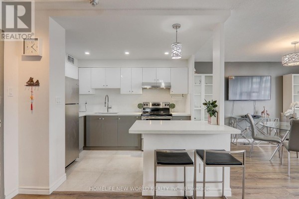 Modern kitchen with white and gray cabinets, stainless steel appliances, and a breakfast bar with stools. - 1412 - 10 Parkway Forest Drive, Toronto