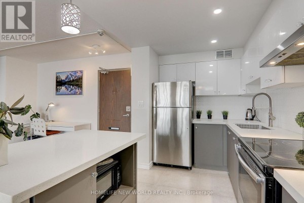 Corner of the kitchen showing stainless steel refrigerator, white countertops, gray cabinets, and a built-in microwave. - 1412 - 10 Parkway Forest Drive, Toronto