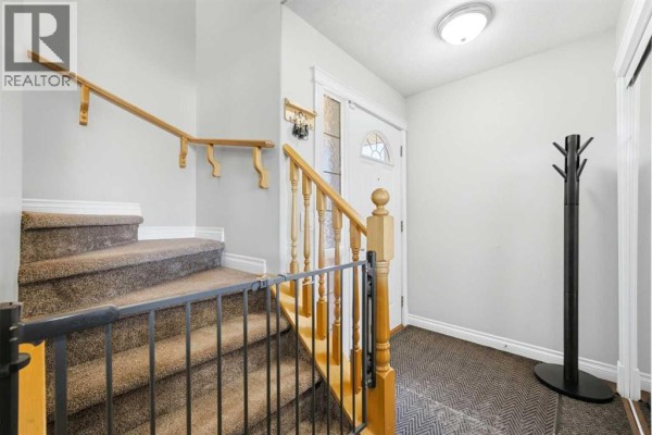 Interior entrance with a carpeted staircase and a coat rack. - 1412 Bayside Avenue Sw, Airdrie
