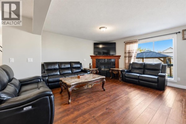 Living room with dark leather sofas, a marble coffee table, and a fireplace. - 1412 Bayside Avenue Sw, Airdrie