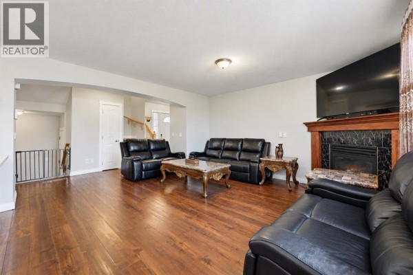 Living room with dark leather seating, a fireplace, and a view of the backyard gazebo. - 1412 Bayside Avenue Sw, Airdrie