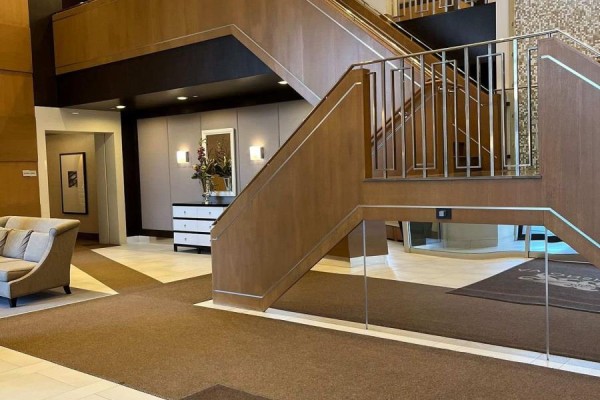 Interior lobby with a grand staircase, seating area, and wood paneling. - 1414 - 100 Harrison Garden Boulevard, Toronto