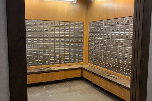 Mailroom with rows of individual metal mailboxes built into wood paneling. - 1414 - 100 Harrison Garden Boulevard, Toronto