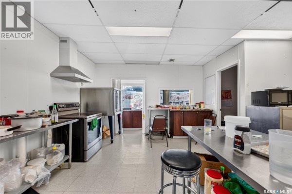 Commercial kitchen with stainless steel appliances, shelving, and storage. - 1415 11th Avenue, Regina