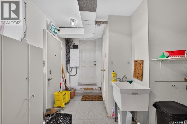 Utility hallway with a utility sink, storage closets, and a white door. - 1415 11th Avenue, Regina