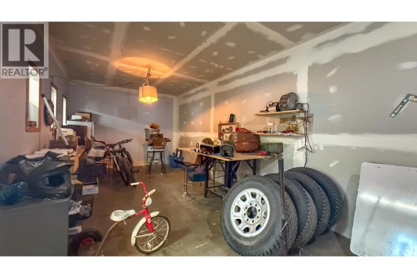 Workshop interior with metal fabrication equipment, tables, shelving, and unfinished projects. - 1415 Dyffryn Road, Lumby