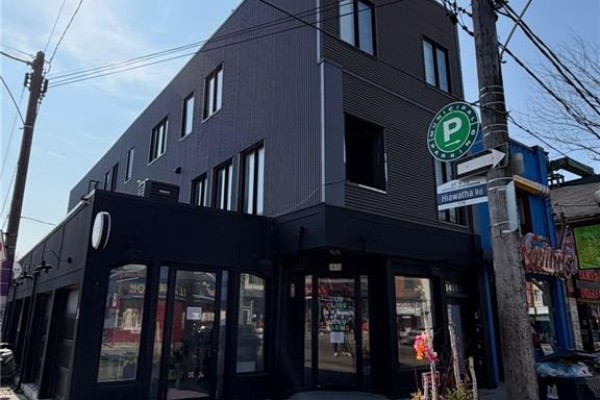 Side angle of the building showing storefronts and modern design elements. - 1415 Gerrard Street E, Toronto