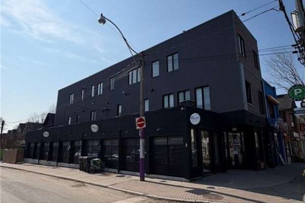 Close-up of the upper floors with windows and signage for 1415 Gerrard Street E. - 1415 Gerrard Street E, Toronto