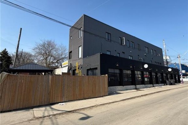 View of the building's facade highlighting large windows and black storefronts. - 1415 Gerrard Street E, Toronto
