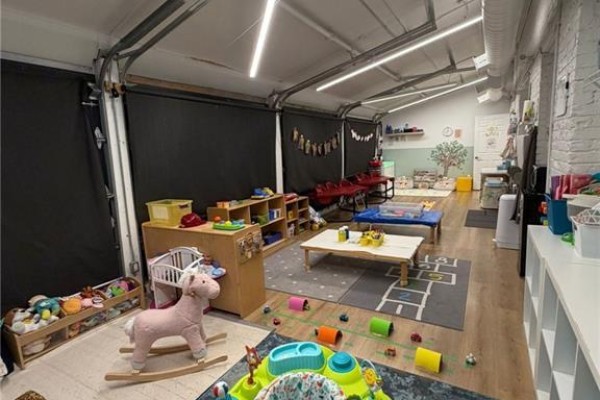 Interior playroom with toys, seating area, and large garage-style door. - 1415 Gerrard Street E, Toronto