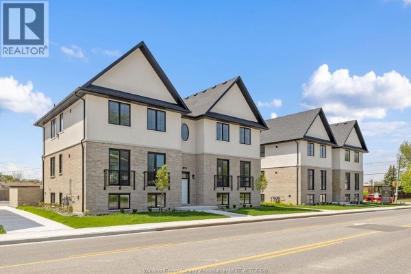 Side view of a modern apartment building with a street in the foreground and trees. - 1415 Lesperance Unit# 2, Tecumseh