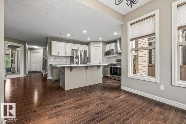 Hallway leading to stairs, with dark hardwood flooring and carpeted stairs - 1416 56 St Sw, Edmonton
