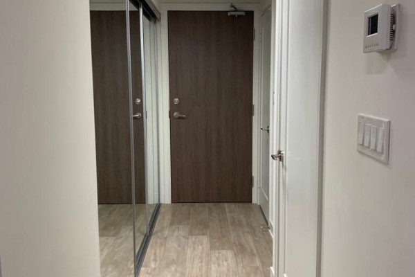 Interior hallway with a large mirrored closet, a wooden door, and a white door. - 1416w - 27 Bathurst Street, Toronto