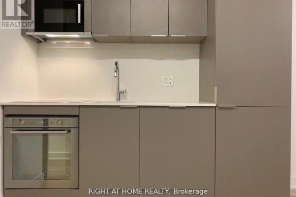 Close-up of a modern grey kitchen with matte cabinets, stainless steel oven, and a white countertop. - 1416w - 27 Bathurst Street, Toronto