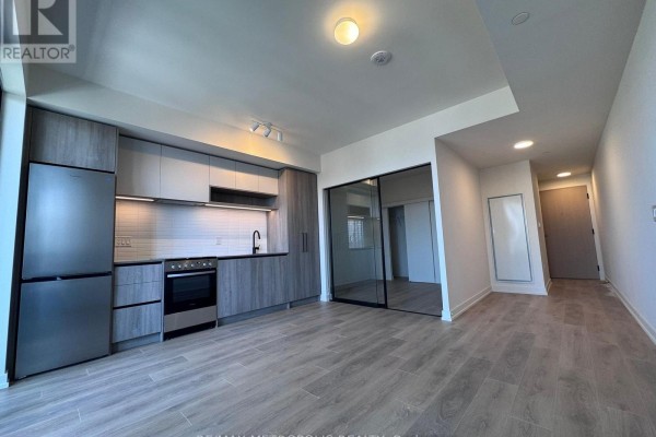 Open concept living area with a modern kitchen and light wood plank flooring. - 1418 - 181 Sterling Road, Toronto