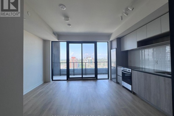 Living room with a balcony and floor-to-ceiling windows offering city views. - 1418 - 181 Sterling Road, Toronto