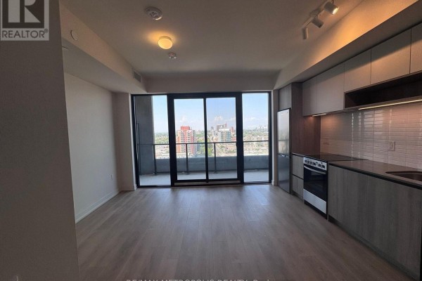 Apartment interior showing the living area, kitchen, and balcony with city views. - 1418 - 181 Sterling Road, Toronto
