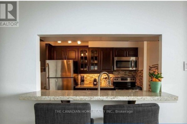 View of a modern kitchen with stainless steel appliances and granite countertop pass-through. - 1418 - 35 Trailwood Drive, Mississauga