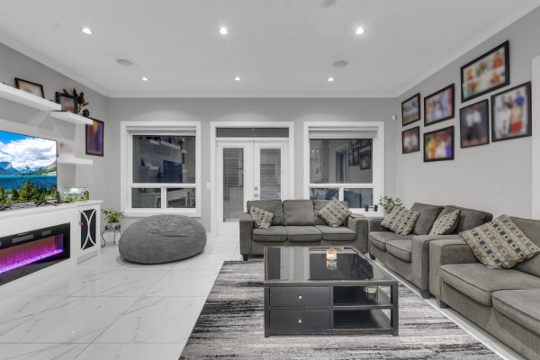Living room with grey sectional sofas, black coffee table, and fireplace. - 14186 Melrose Drive, Surrey