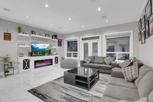 Living room with grey sectional sofas, modern entertainment unit, and fireplace. - 14186 Melrose Drive, Surrey