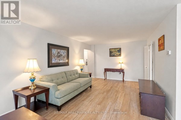 Living room with light wood floors, a green sofa, two side tables with lamps, and a dark wood TV stand. - 1419 - 1 Massey Square, Toronto