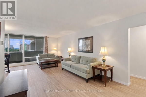 Living room with light wood floors, two sofas, side tables with lamps, and a large window with curtains. - 1419 - 1 Massey Square, Toronto