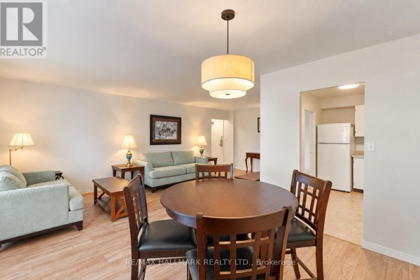 Living and dining area with light wood floors, two sofas, a round wooden dining table with four chairs. - 1419 - 1 Massey Square, Toronto