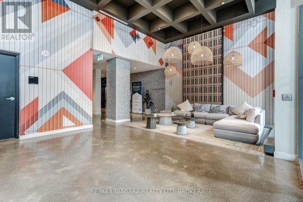 Contemporary lobby seating area with a large sectional sofa and colorful geometric wall art. - 1419 - 10 Abeja Street, Vaughan