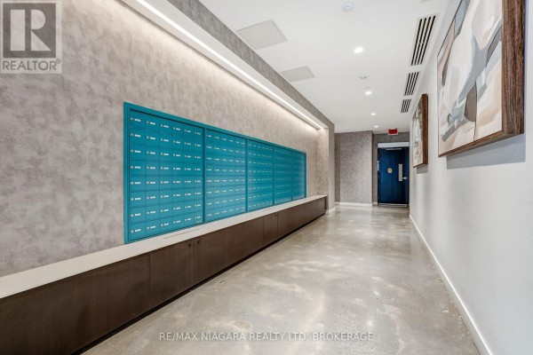 Condominium building hallway with a long row of teal mailboxes and modern art. - 1419 - 10 Abeja Street, Vaughan
