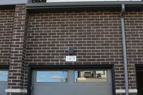 Close-up of dark brick exterior wall with garage door and unit number 1419. - 1419 - 1695 Dersan Street, Pickering