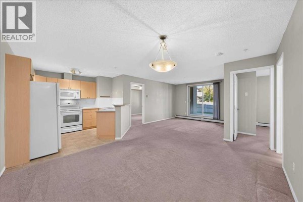 Open concept living and dining area with light grey walls and beige carpet. - 142, 428 Chaparral Ravine View Se, Calgary