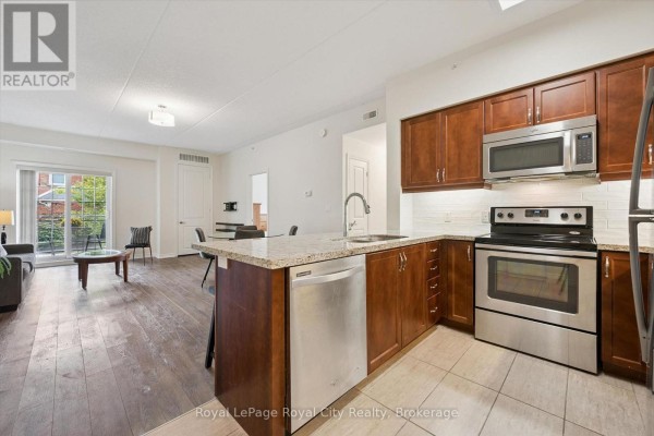 Modern kitchen with granite countertops, stainless steel appliances, and dark wood cabinets. - 142 - 1077 Gordon Street, Guelph