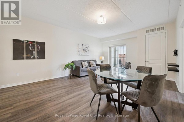 Living and dining area with a glass-top dining table, gray upholstered chairs, and a sofa. - 142 - 1077 Gordon Street, Guelph