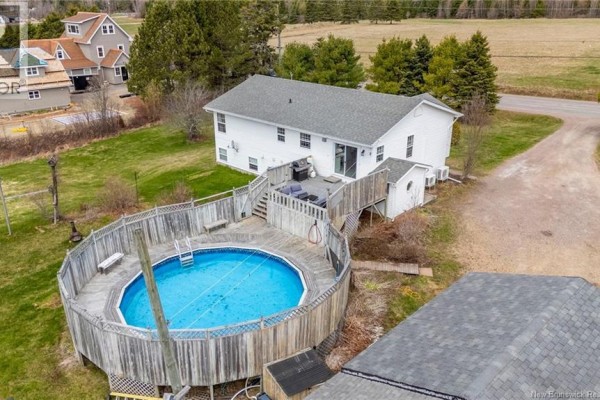 Aerial view of a white house with a wooden deck, above-ground pool, and surrounding lawn. - 142 Fairfield Road, Sackville