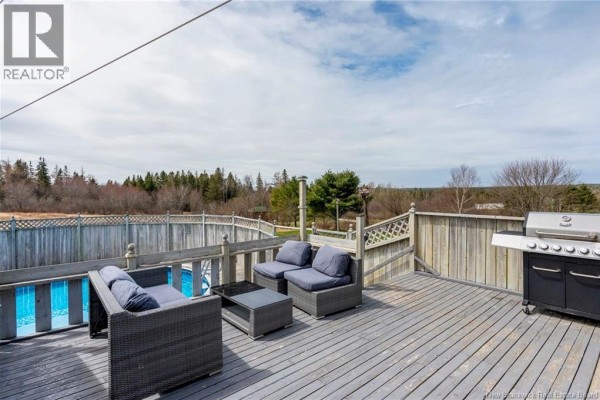A wooden deck with outdoor furniture, a grill, and a view of an above-ground pool. - 142 Fairfield Road, Sackville