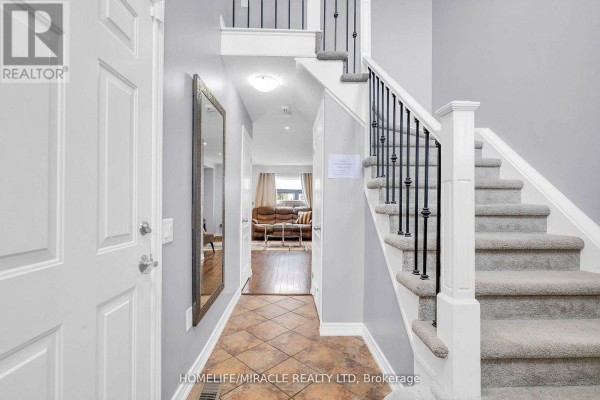 View from above of the foyer showing a white chandelier, stairs, and the front door. - 142 Marion Street, Shelburne