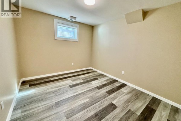 Unfurnished room with neutral walls, grey plank flooring, and a small window. - 142 Meadow Drive, Hinton