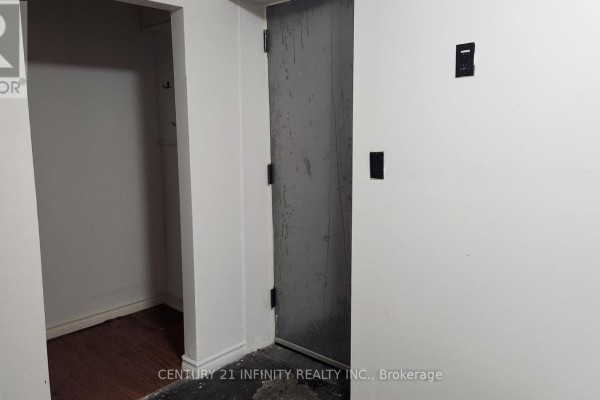 Storage closet with dark wooden floor and adjacent grey metal door. - 142 Simcoe Street S, Oshawa