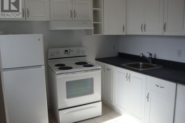 White kitchen with white cabinets, black countertop, stove, refrigerator, and sink. - 142 Ste Cecile Street, Ottawa