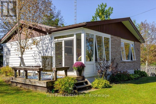 Rear exterior view of a sunroom addition with large windows and a wooden deck. - 1420 Eastview Drive, Selwyn