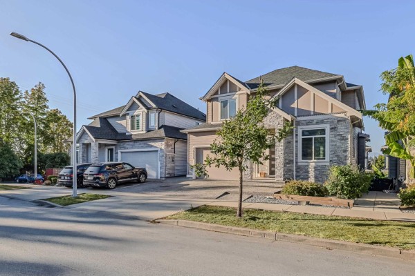 Side view of the house, showing the garage and exterior details, with neighboring properties visible. - 14215 61b Avenue, Surrey
